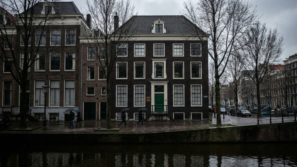 The narrow brick building of the Anne Frank House on the Amsterdam canal.	